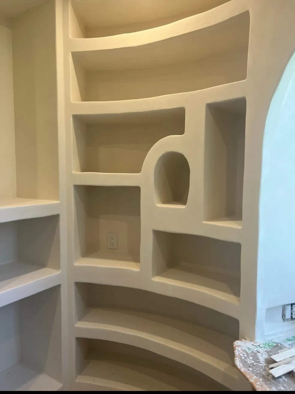 Custom sculpted plaster built-in shelving unit with curved arches and display niches
