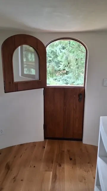 Plaster walls with custom arched wood door and window — treehouse interior