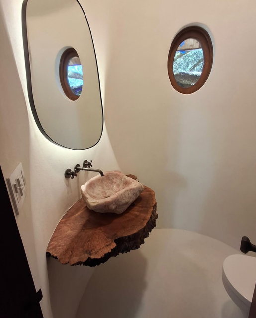 Custom plaster bathroom in treehouse — smooth white plaster walls with organic stone sink