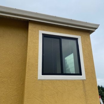 Yellow EIFS exterior with white trim detail around dark-framed window