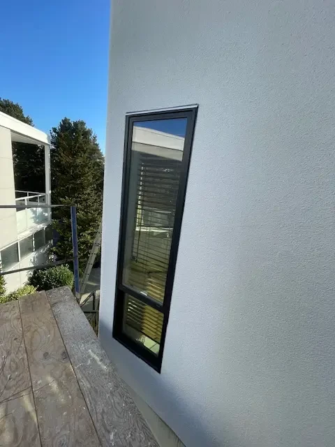Clean stucco finish around black-framed window on modern exterior