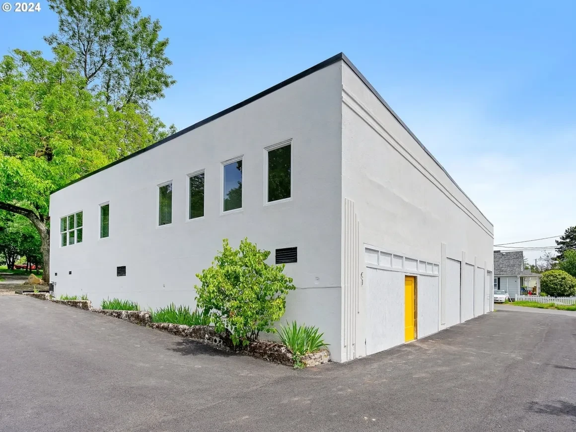 Commercial stucco building with yellow door and black-framed windows