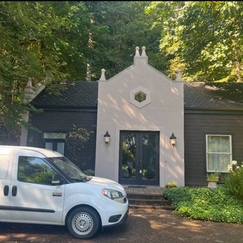 White stucco gothic-style home with Dream Plastering van