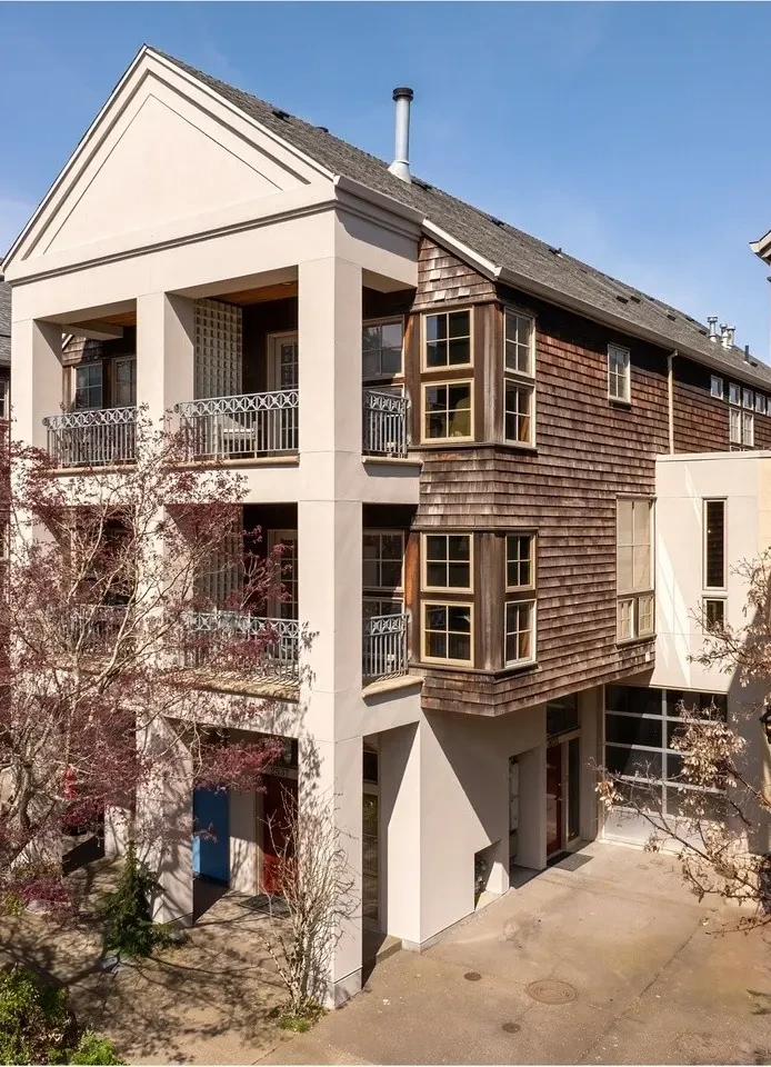 Multi-story building with stucco columns, cedar shingles and iron balconies