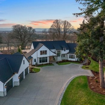 Modern white stucco farmhouse aerial view with circular driveway