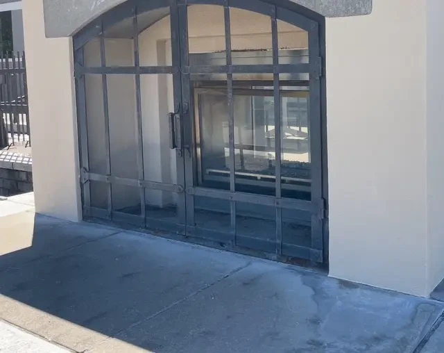 Stucco arched commercial entry with steel and glass doors