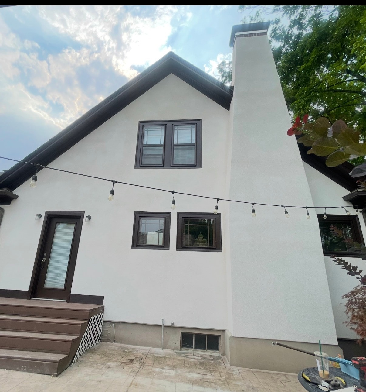 Freshly restored white stucco gable and chimney with black trim